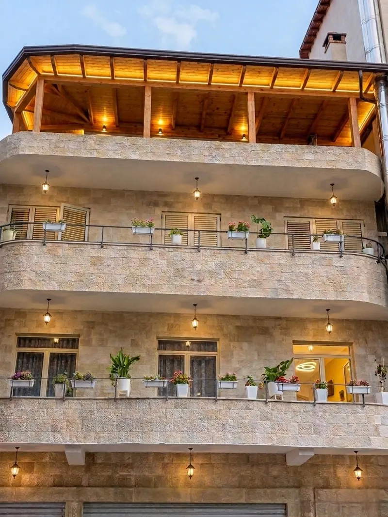 Vila HK at dusk: stone balconies with lanterns and a wooden roof terrace