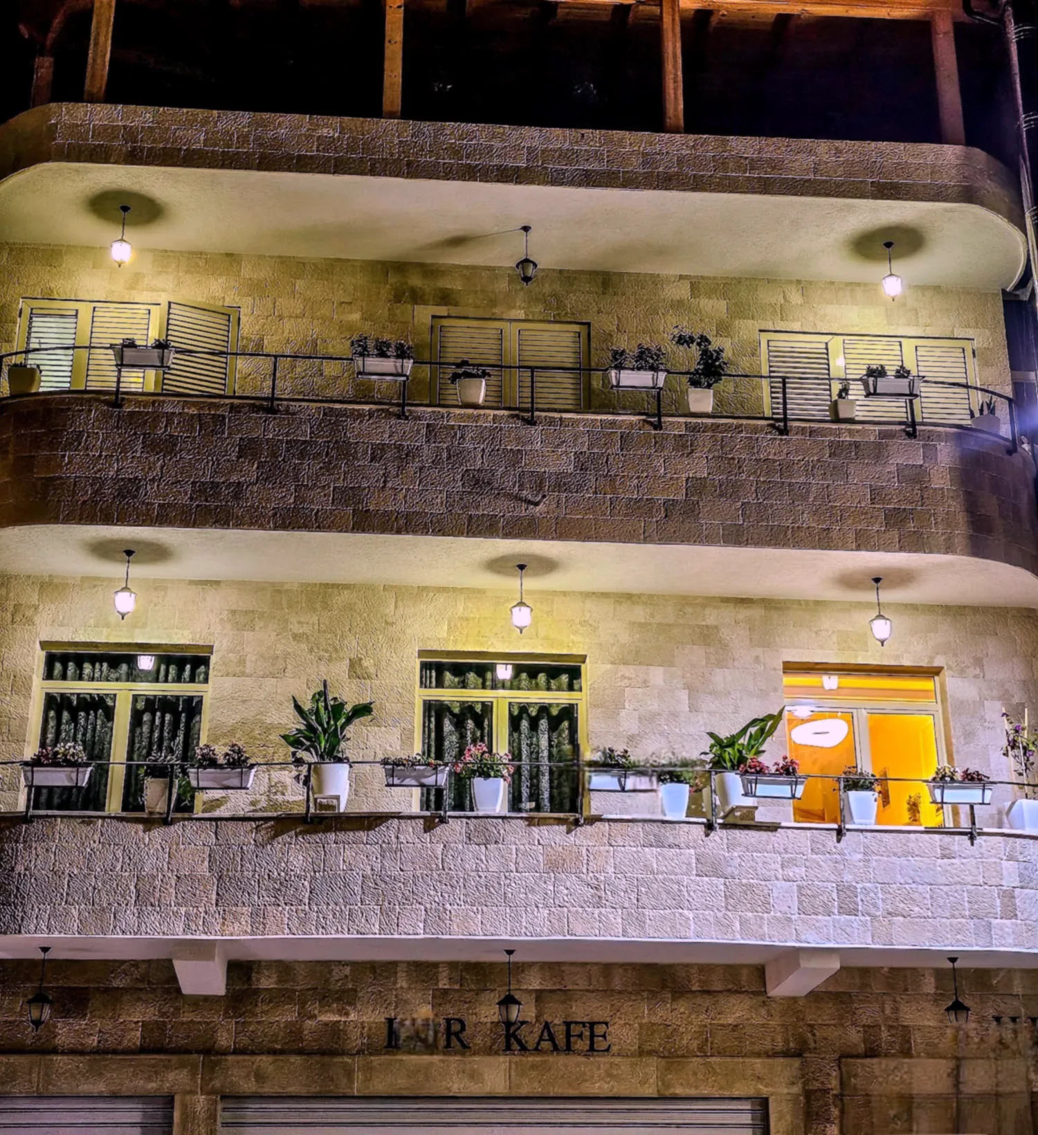 Vila HK at night: stone balconies, lanterns and flower boxes